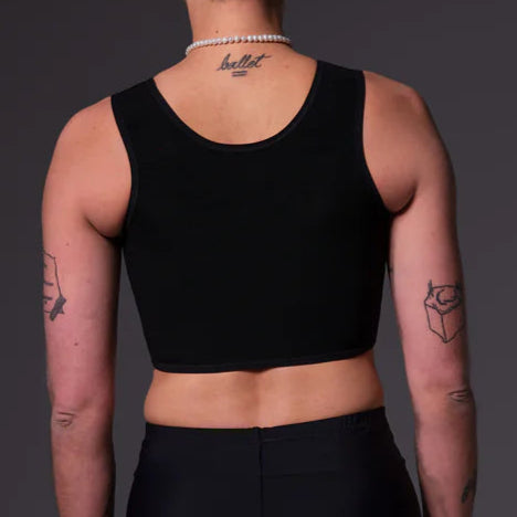 Person wearing a black swim binder top and black shorts against a gray background