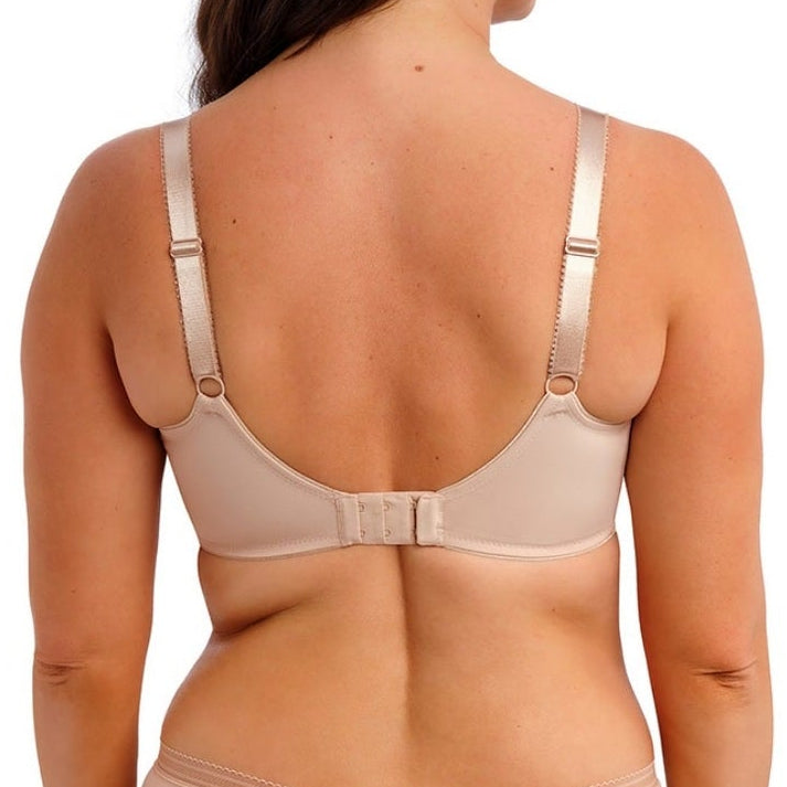 Woman wearing a beige bra and panties set on a white background