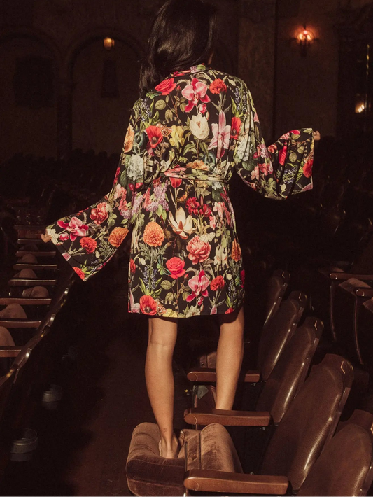 Person wearing a floral robe standing in a theater with dim lighting