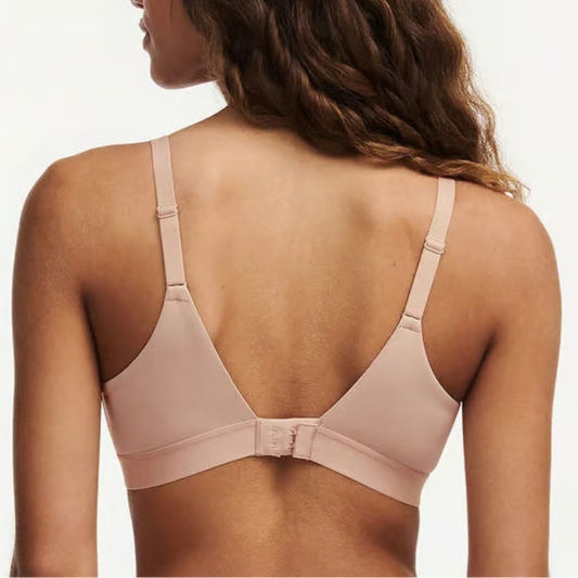 Woman wearing a beige bra against a plain background