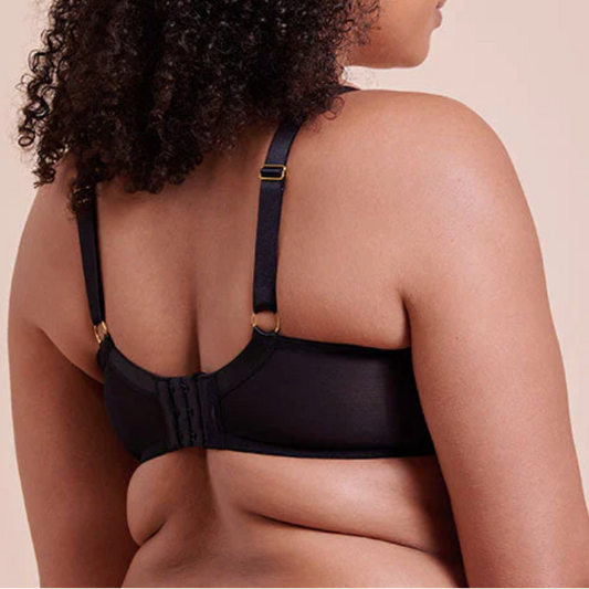 Woman wearing a black bra against a beige background