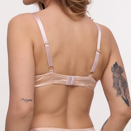 Woman wearing a beige lingerie set on a plain background