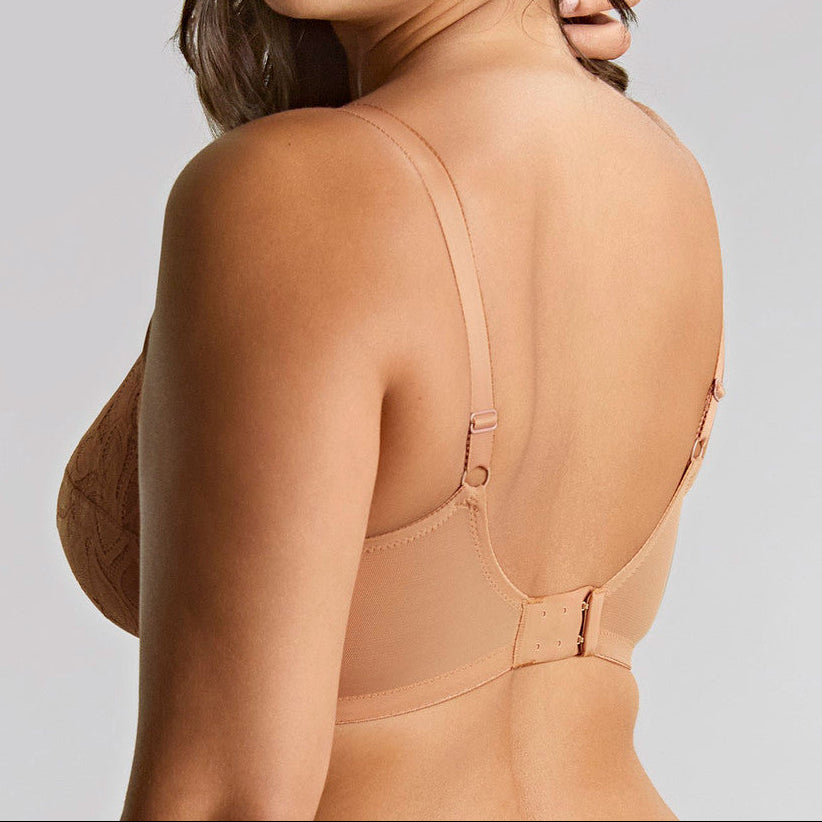 Woman wearing a beige bralette against a gray background