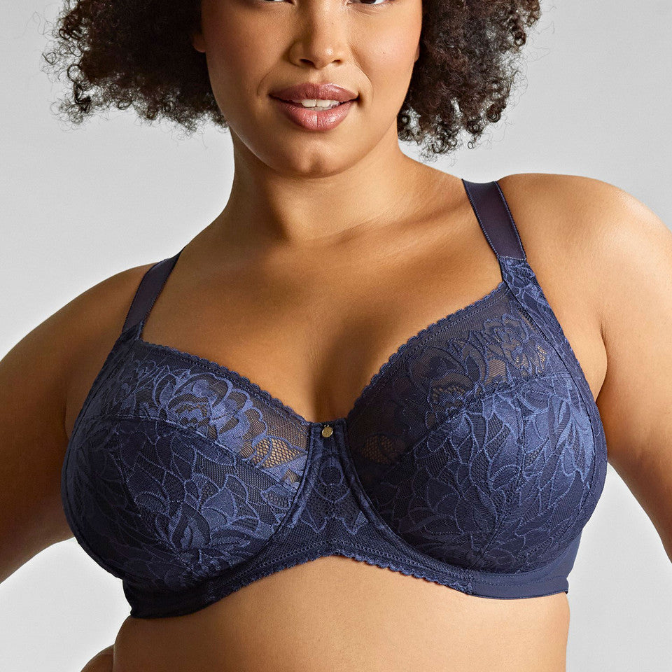 Woman wearing a navy blue lace bra against a gray background