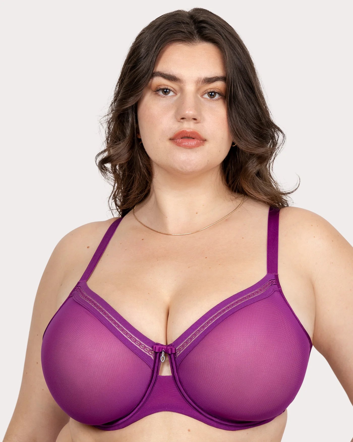 Woman wearing a purple bra against a plain background
