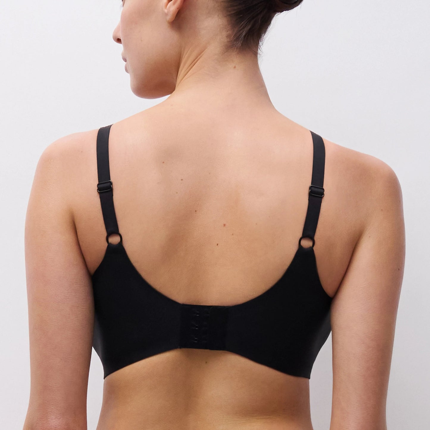 Woman wearing a black bra against a plain background