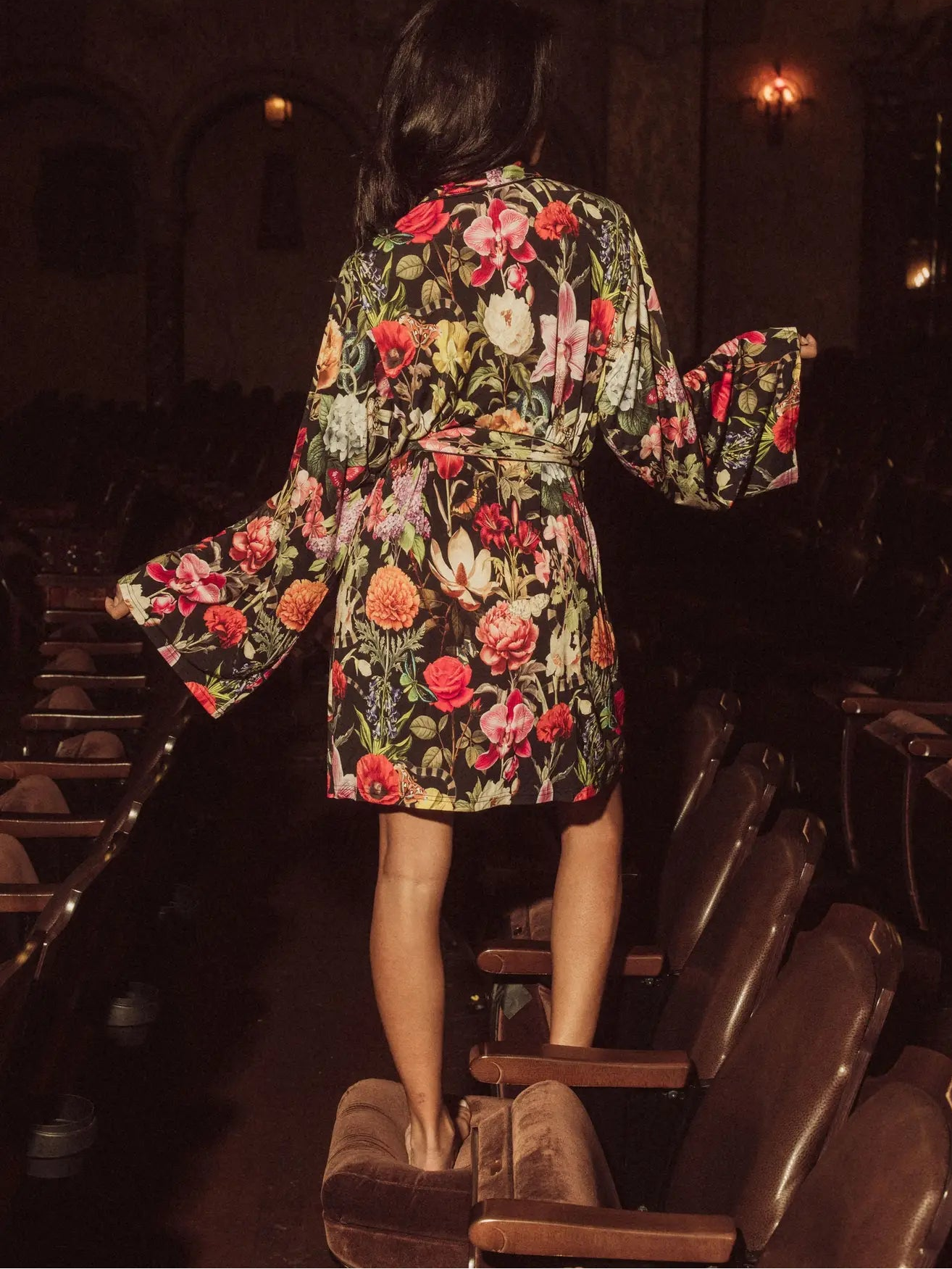 Person wearing a floral robe standing in a theater with dim lighting