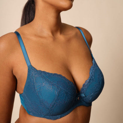 Woman wearing a blue bra against a beige background