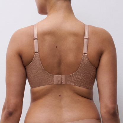 Woman wearing a beige bra against a plain background