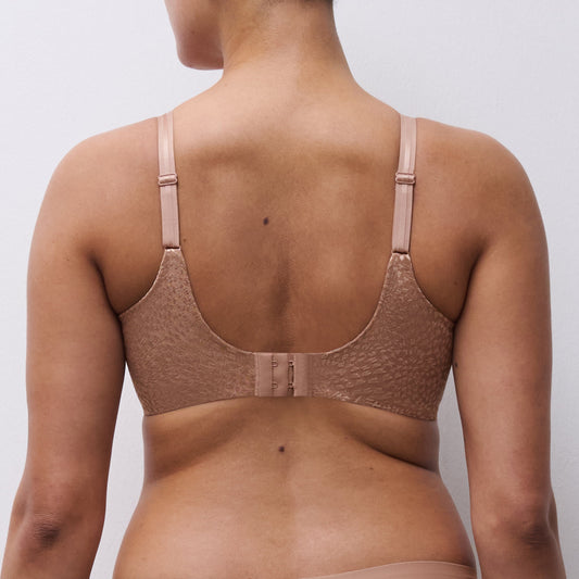 Woman wearing a beige bra against a plain background