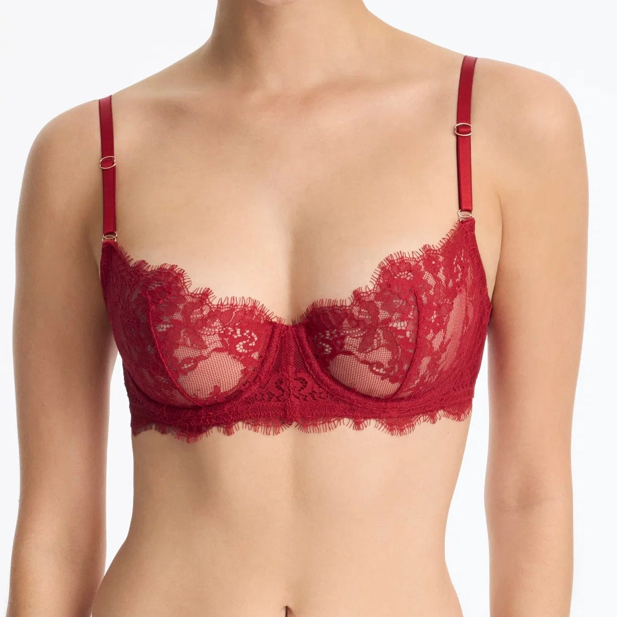 Woman wearing a red lace bra against a white background