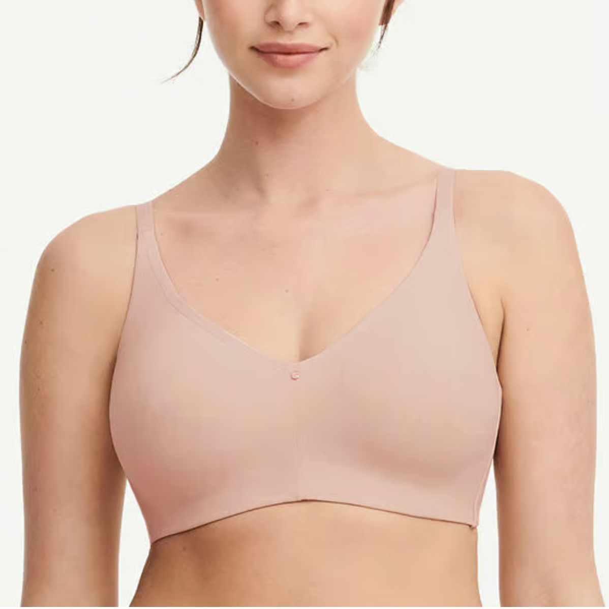 Woman wearing a beige bralette against a plain background