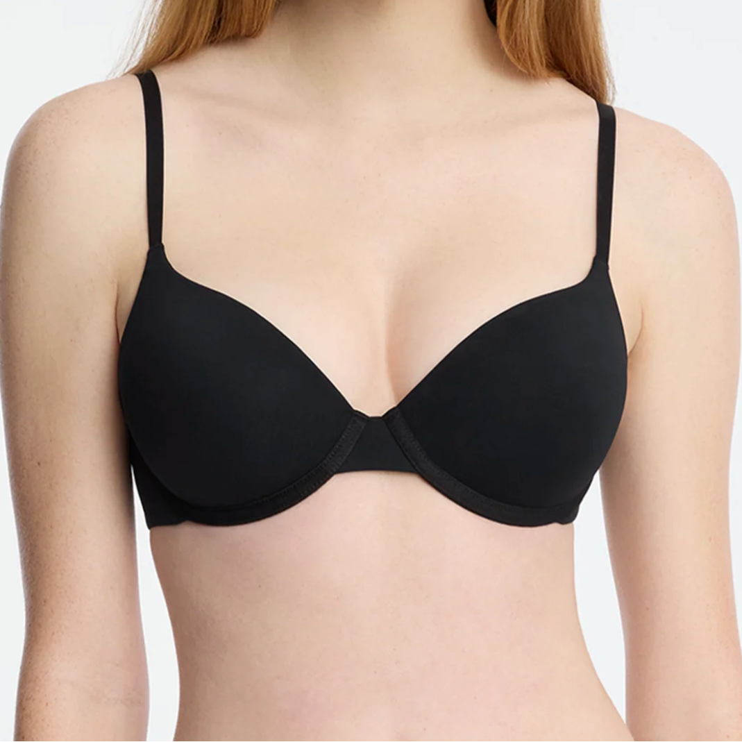 Woman wearing a black bra against a plain background