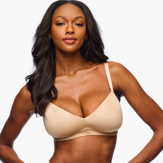 Woman wearing a beige bralette against a plain white background