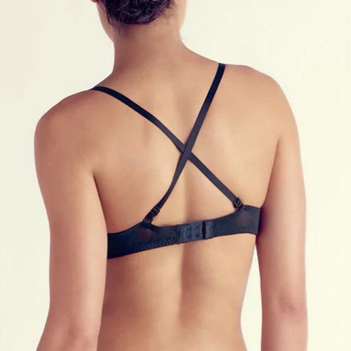 Person wearing a black strappy bikini on a plain background